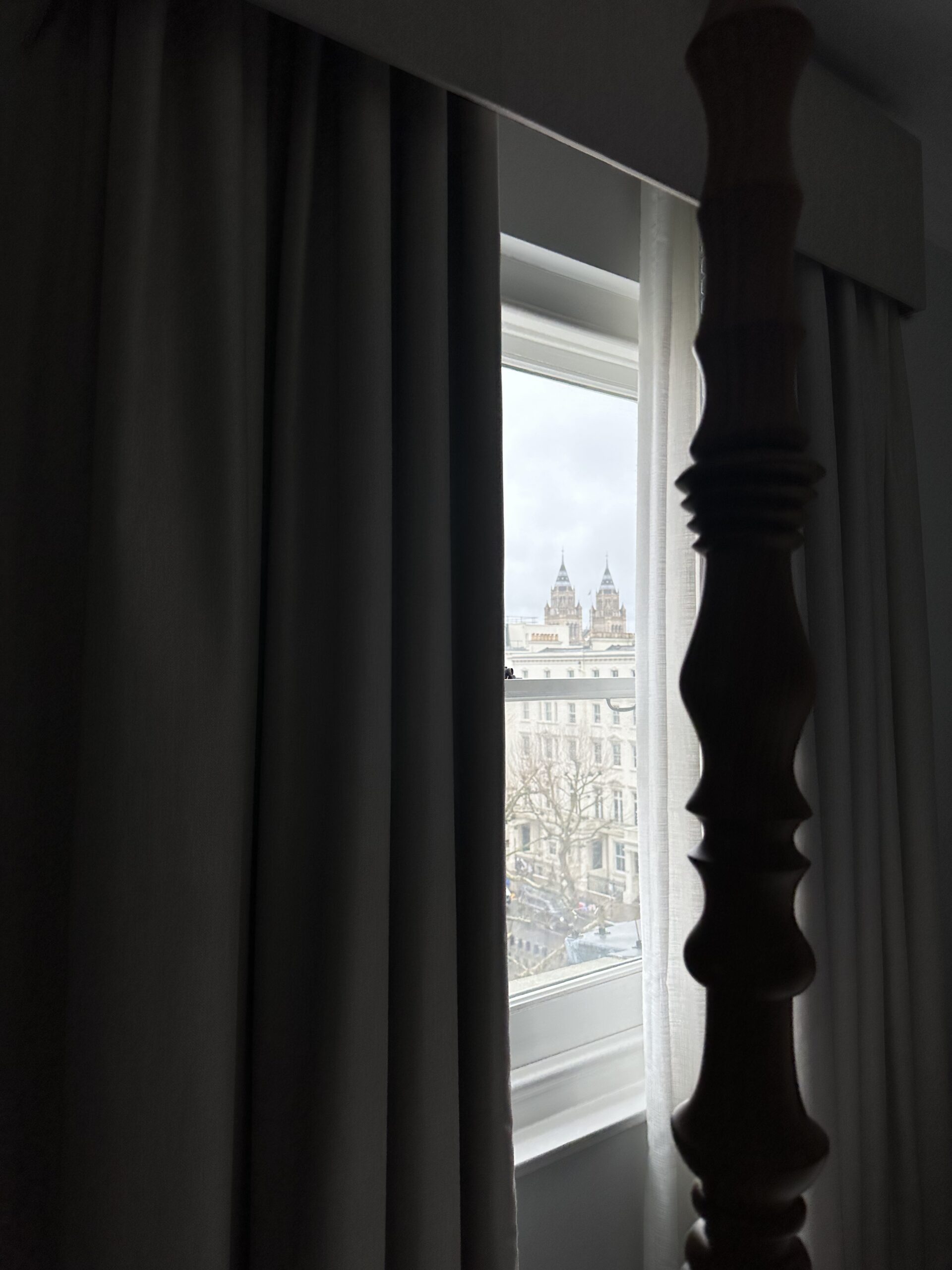 View of London through a window framed by dark curtains.